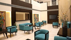 A spacious lobby with multiple seating areas, a large flat-screen TV, and artwork on the walls.