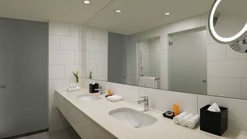 A modern bathroom with two sinks, a large mirror, and a vanity with toiletries.