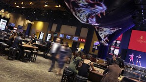 Un vestíbulo de hotel concurrido con una pantalla digital grande que muestra un tigre, múltiples cajeros automáticos y una zona de bar.