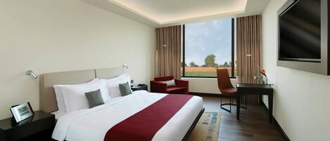 Una habitación de hotel con una cama grande, un escritorio, una silla y un televisor.