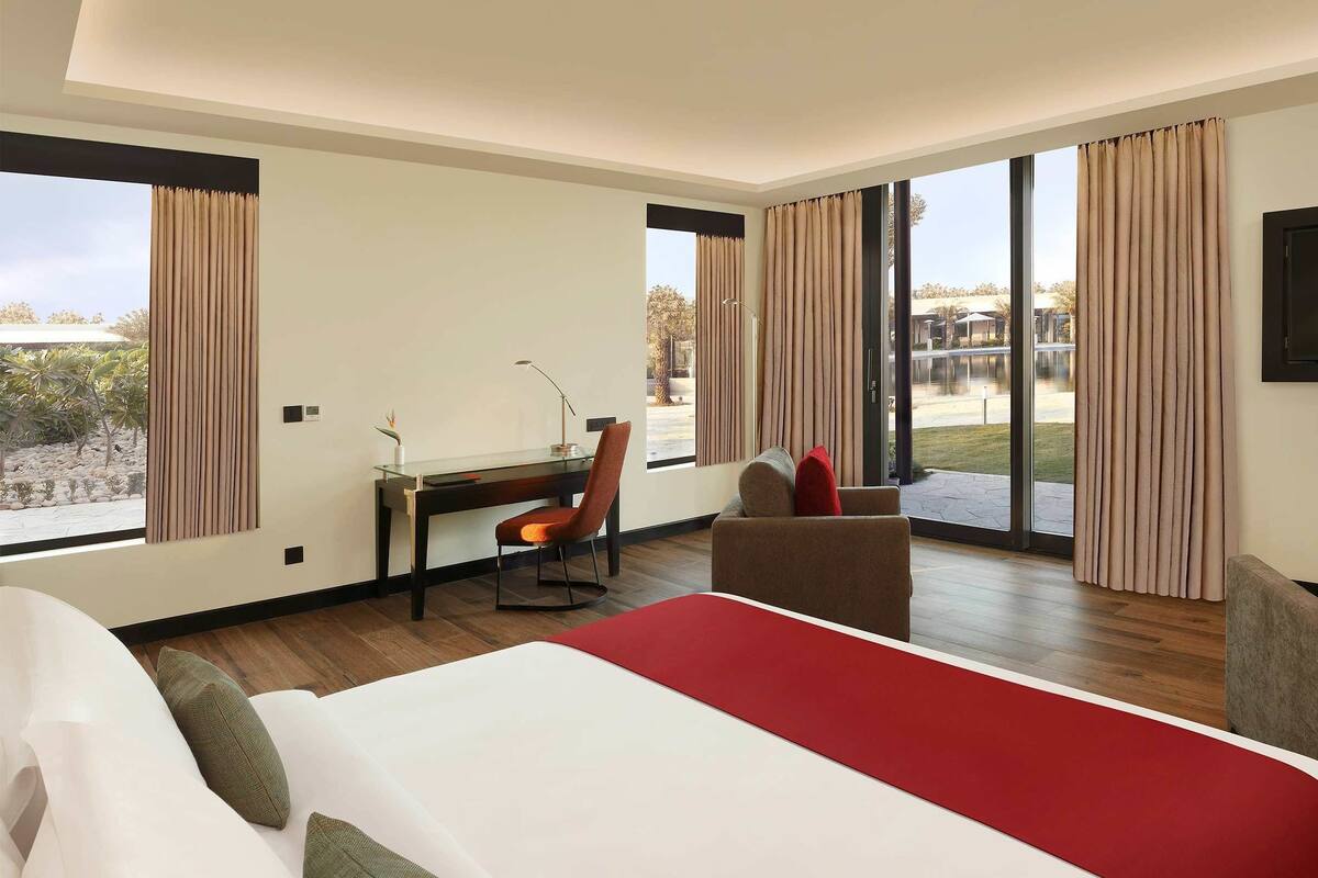 A hotel room with a large bed, a desk, a chair, and a TV.