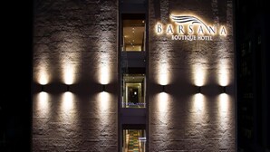 A building with a sign reading "Barsana Boutique Hotel" and a visible interior corridor with a checkered floor.