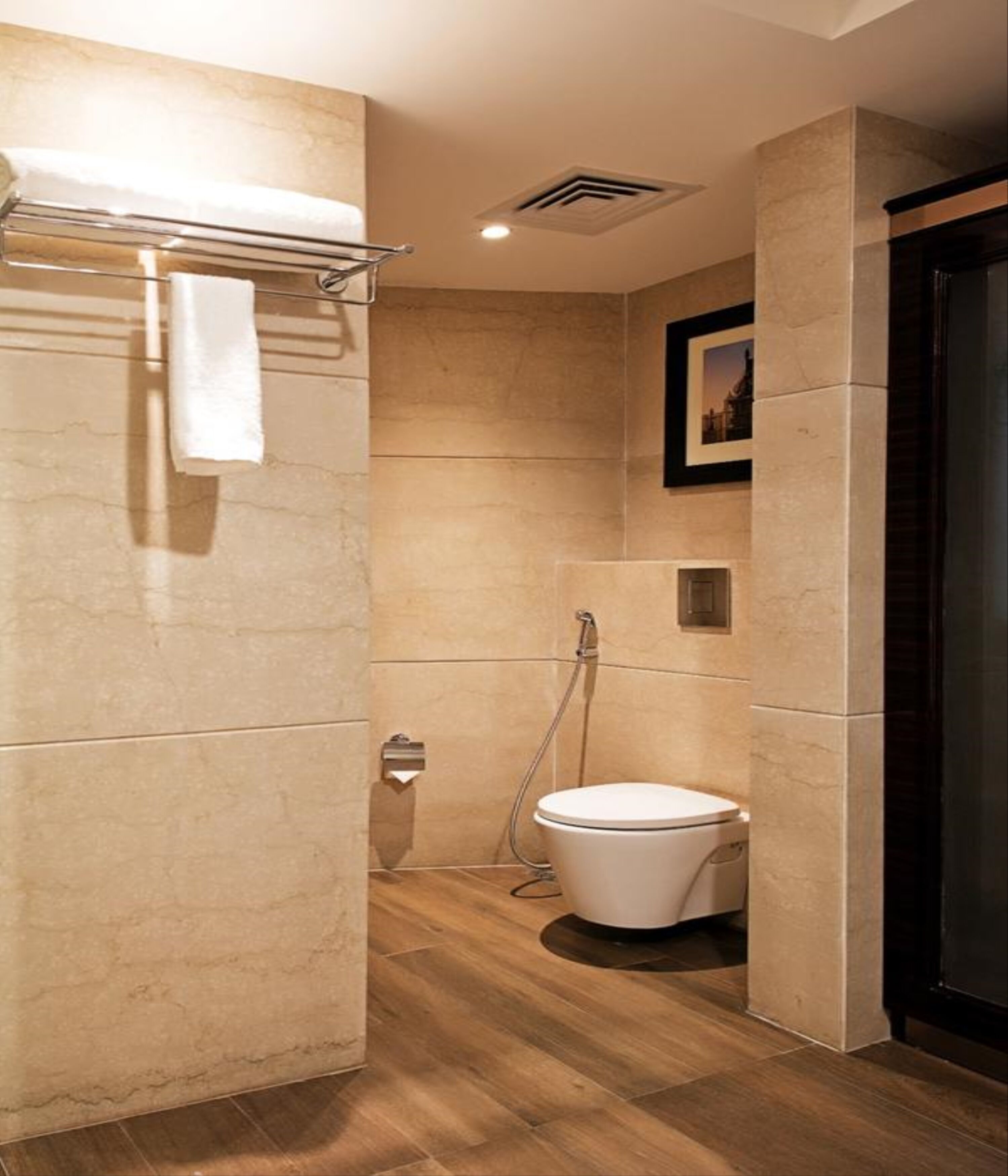 A modern bathroom with a shower, toilet, and towel rack.