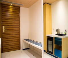 A modern kitchen with a wooden door, a built-in bench, and a microwave.