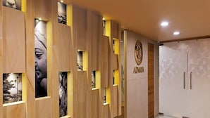 A reception area with a wooden panel wall, a patterned carpet, and a door with a circular emblem.