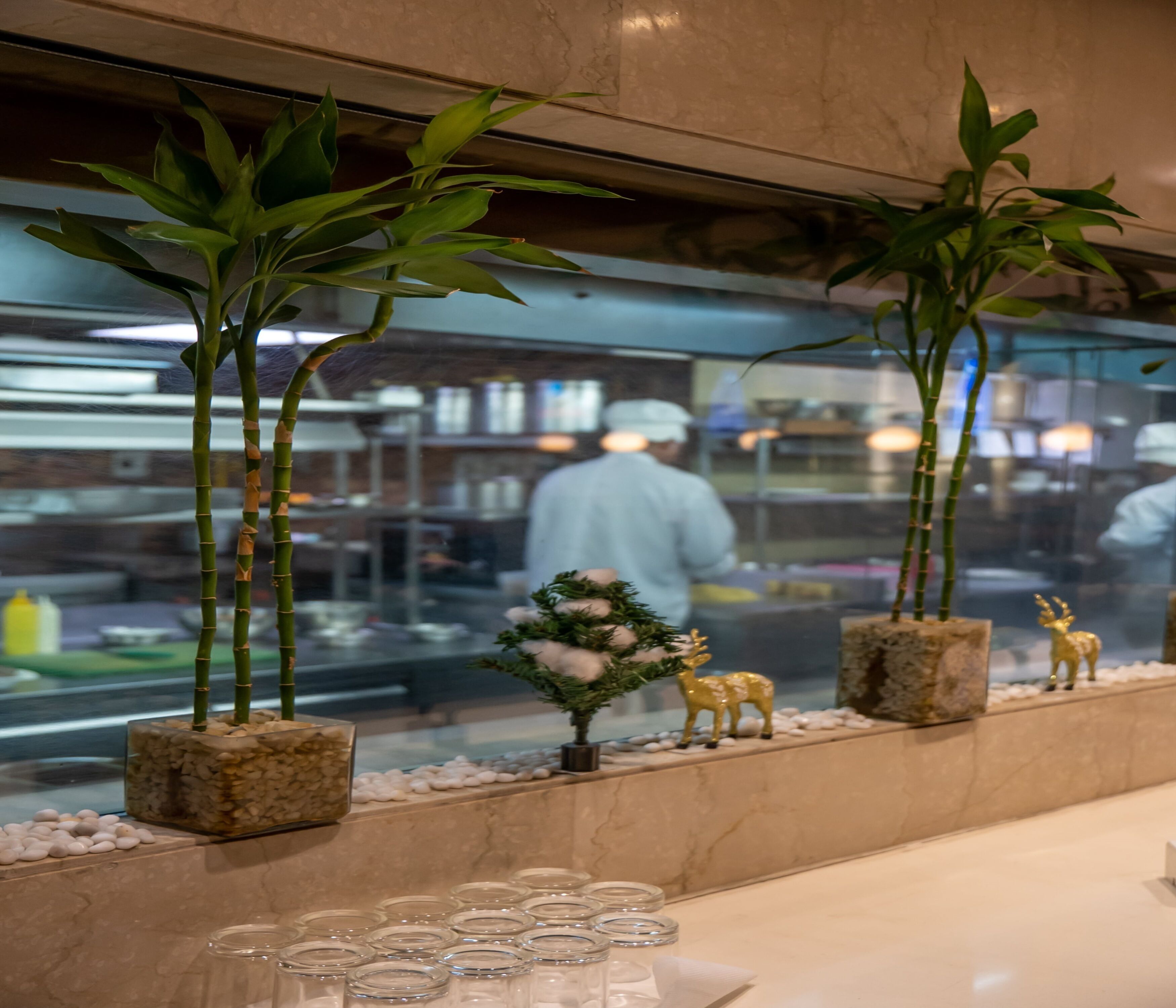 Un interior de restaurante con mostrador de mármol, plantas en macetas y elementos decorativos.