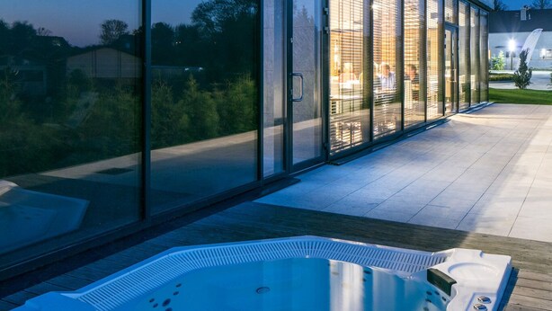Un edificio moderno con amplios ventanales y un jacuzzi exterior.