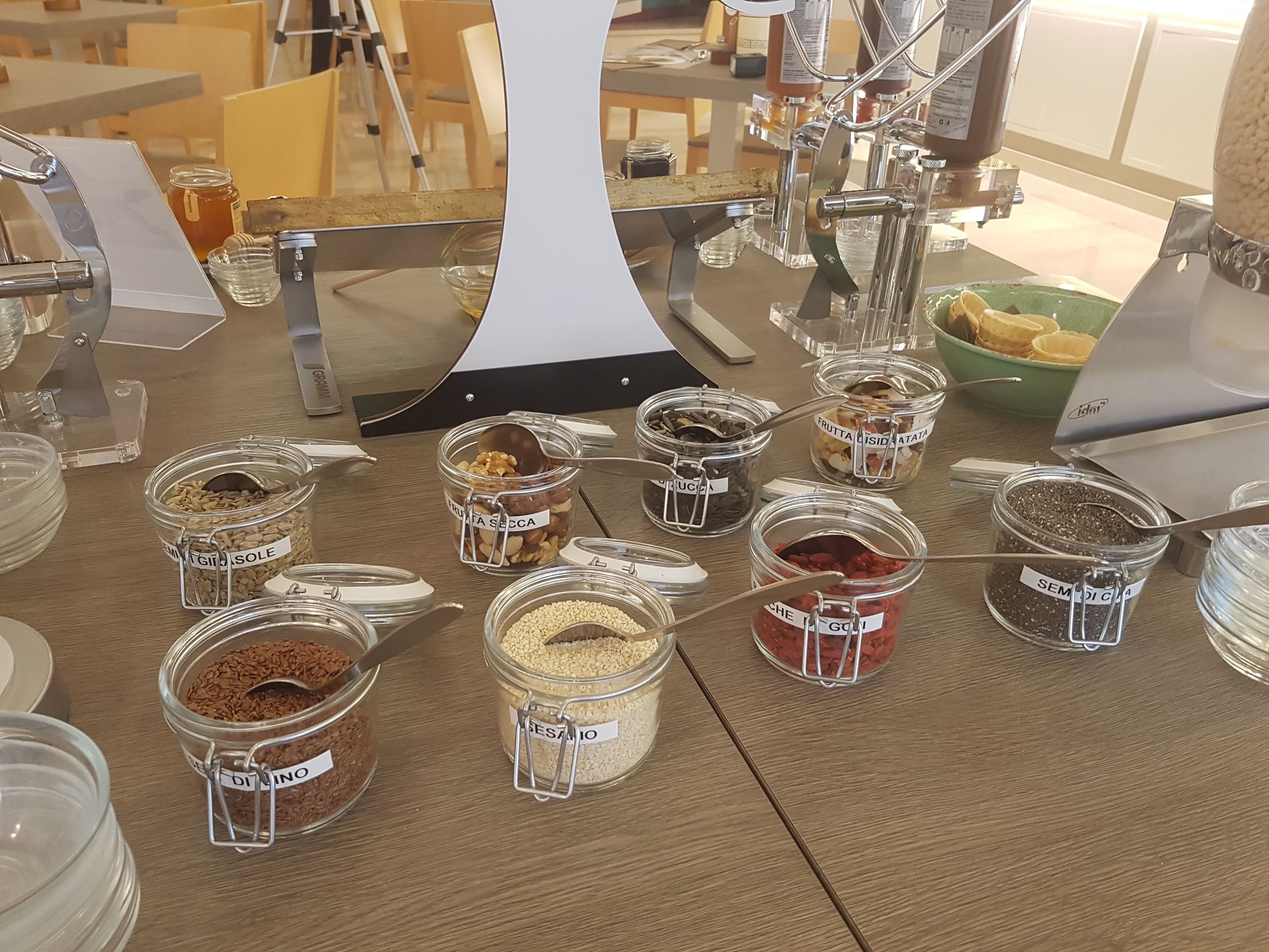 Une variété d’aliments en conserve, présentés dans des bocaux en verre avec des étiquettes, disposés sur une table en bois dans un coin repas.