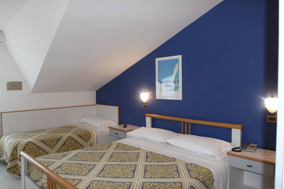 Un dormitorio con dos camas individuales, cabeceros de madera, mesitas de noche y una lámpara de pared.