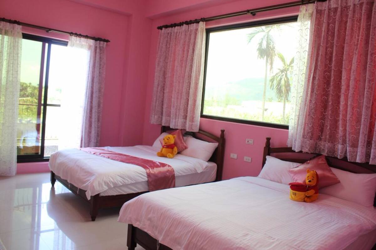 A pink-themed bedroom with two beds, each with a teddy bear.