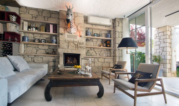 Ein Wohnzimmer mit Kamin aus Stein, einer Zebra-Skulptur und einem großen Fenster.