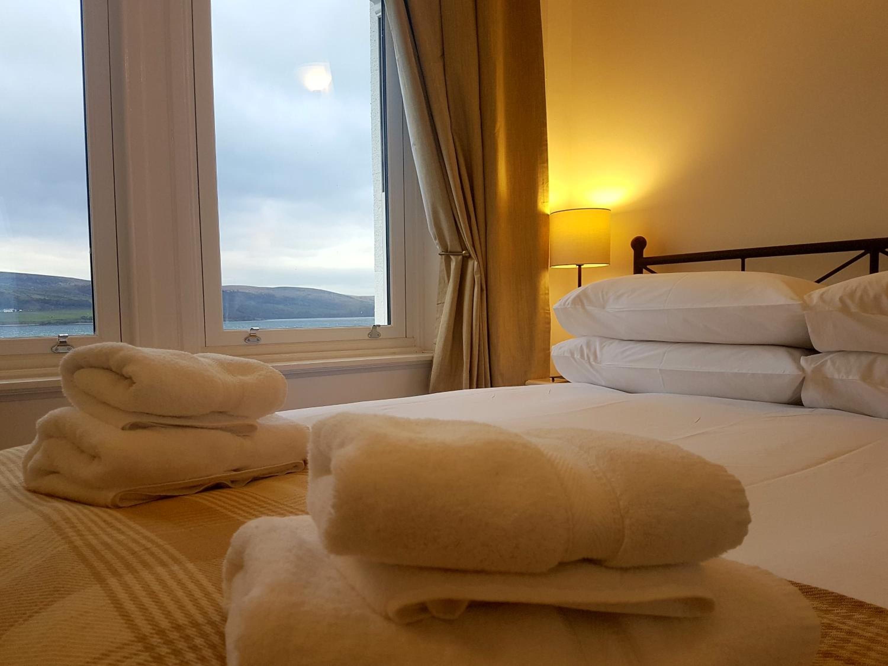 A hotel room with a bed, a window with curtains, and a lamp.
