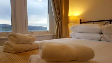 A hotel room with a bed, a window with curtains, and a lamp.