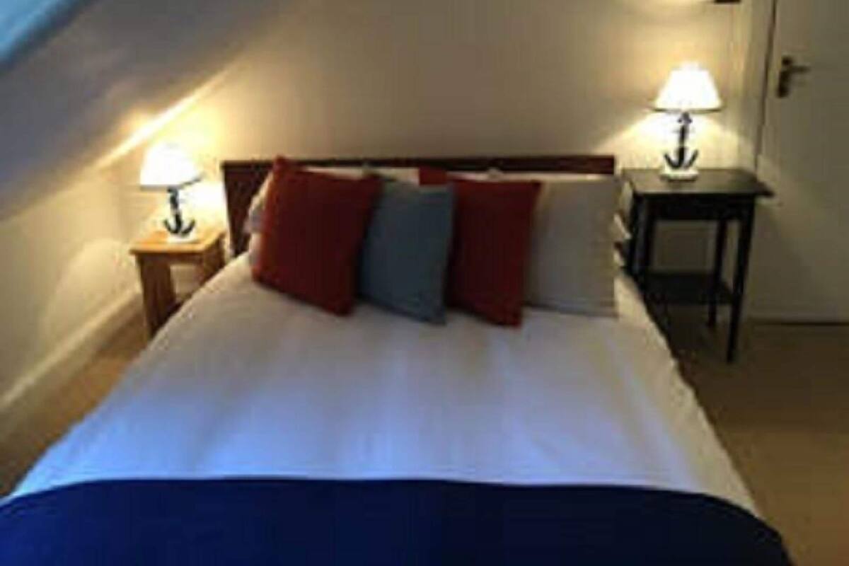 A single bed with a white duvet, two bedside tables with lamps, and a door to the right.