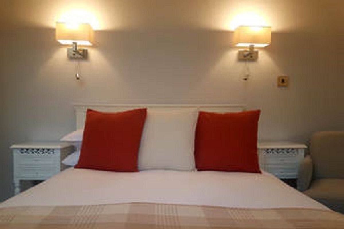 A hotel room with a bed, two bedside lamps, and a nightstand.
