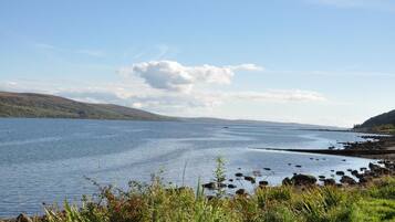 A calm lake with a rocky shoreline and distant hills.