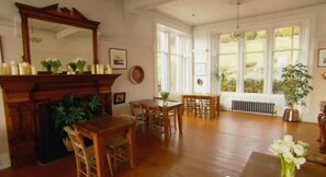 A spacious room with a fireplace, wooden furniture, and large windows. - Kames Hotel (Tighnabruaich)