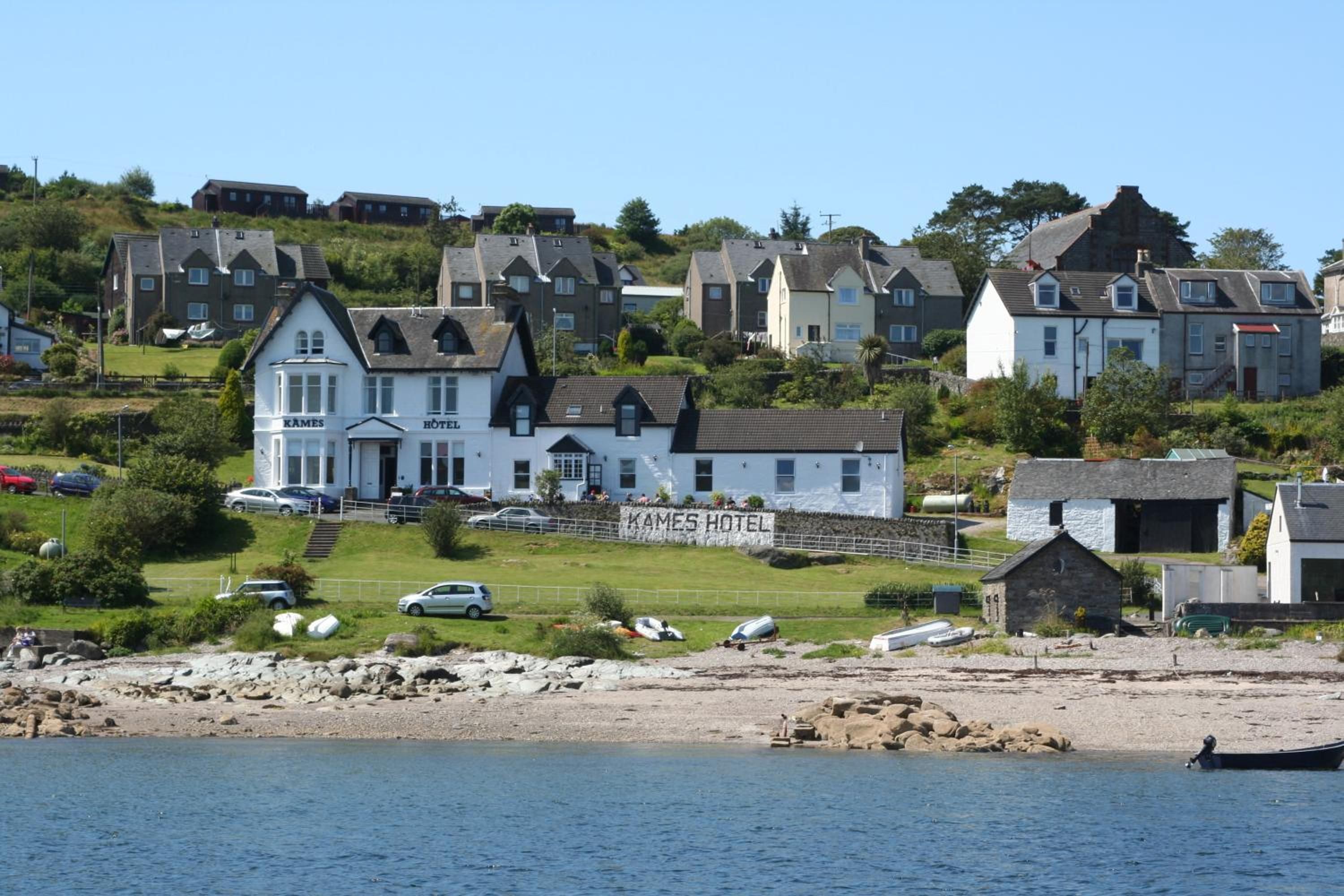Un hôtel situé sur la côte, reconnaissable à son enseigne bien visible, composé de plusieurs bâtiments et donnant sur une plage.