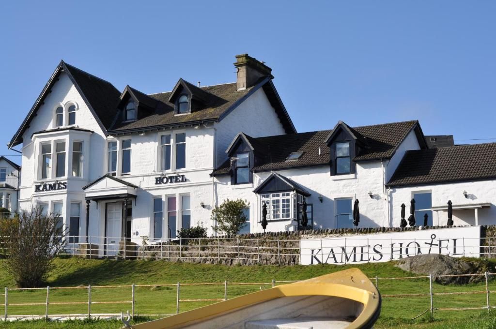 A white building with a sign reading 'KAMES HOTEL' and a boat in the foreground.