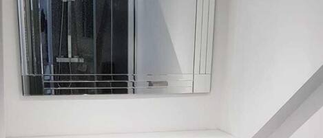 Un baño pequeño y blanco con lavamanos pedestal, un inodoro y un espejo sobre el lavamanos.