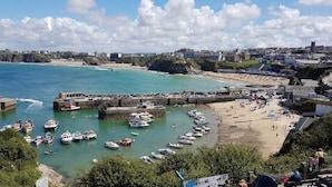 Une ville côtière dotée d’un port rempli de bateaux, d’une plage de sable et de bâtiments qui bordent la côte.
