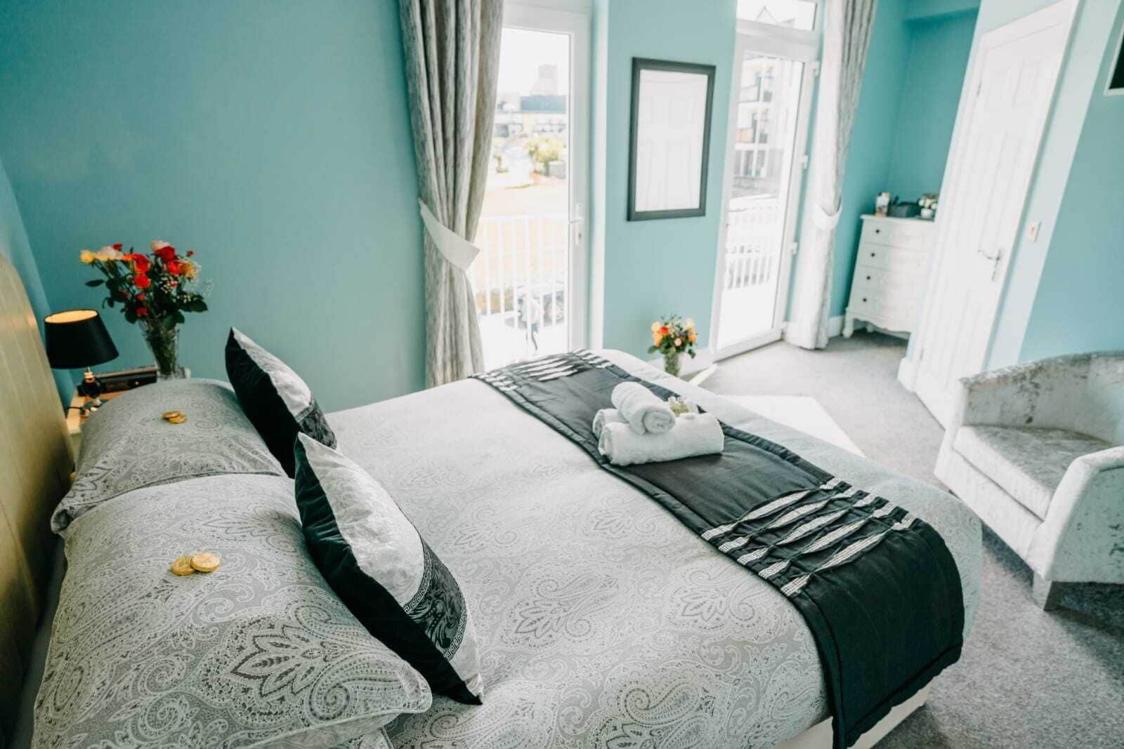 A bedroom with a large bed, two bedside tables, a chair, and a view of the outside.