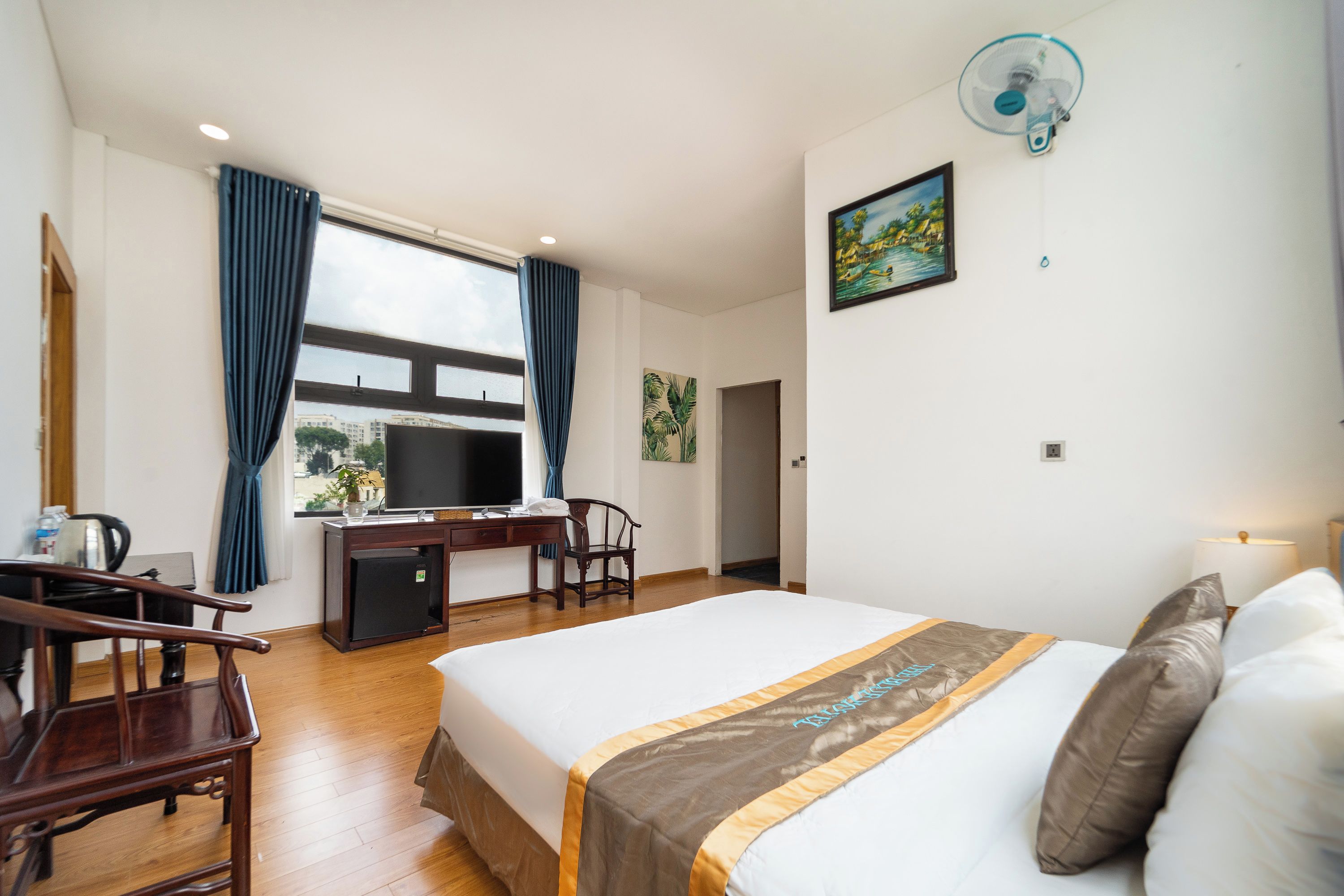 Une chambre d’hôtel équipée d’un lit, d’un bureau, d’une chaise, d’une télévision et d’une fenêtre avec des rideaux.