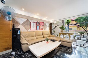Eine moderne Hotelhalle mit einem beigen Ecksofa, einem Marmor-Couchtisch und einem Wandventilator.