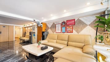 Un hall de hotel con una recepción, un sofá, una mesa de centro y una pared con carteles informativos.