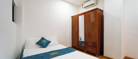 A bedroom with a bed, a wardrobe, and an air conditioning unit.