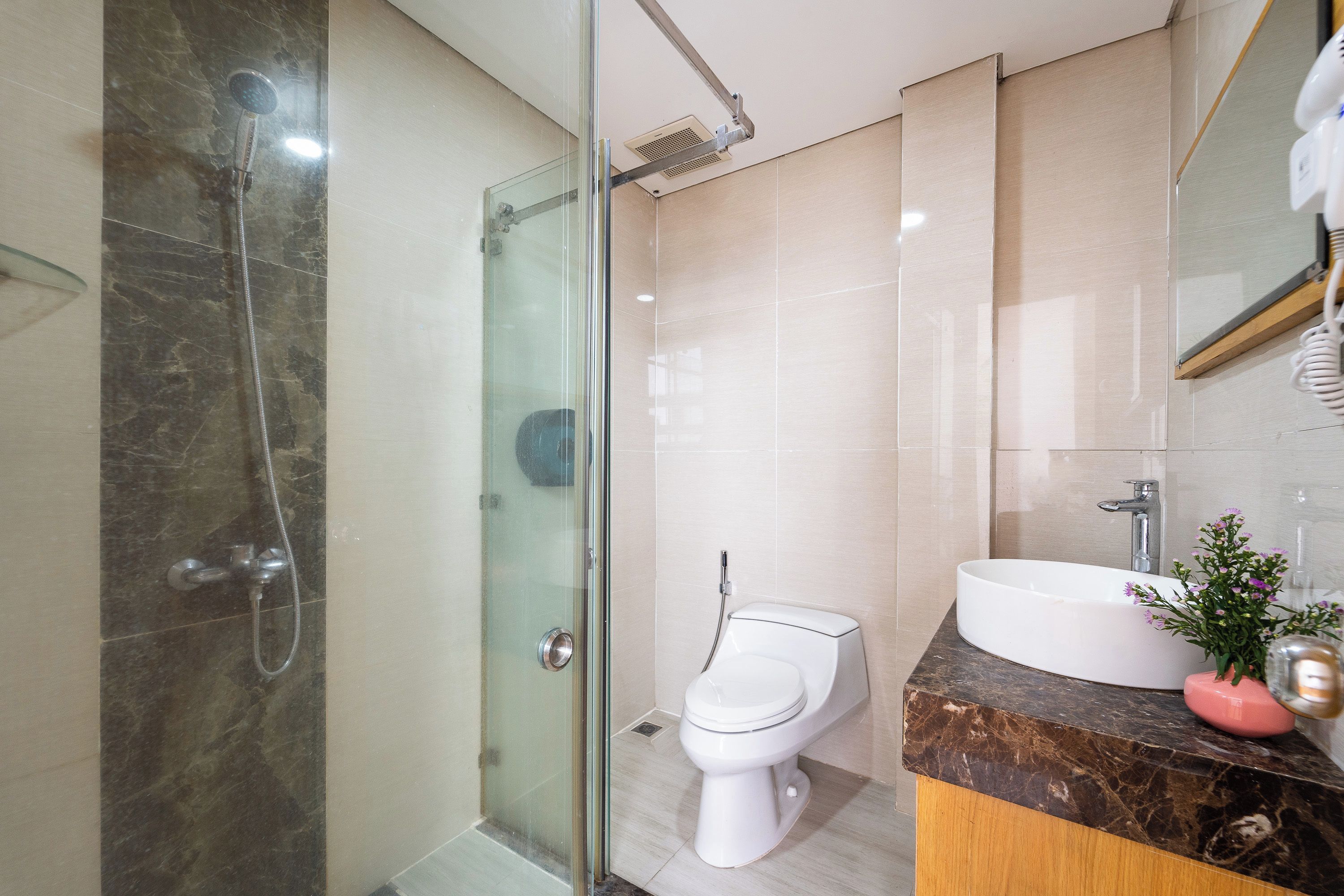 A modern bathroom with a glass-enclosed shower, a white toilet, and a vanity with a sink and mirror.