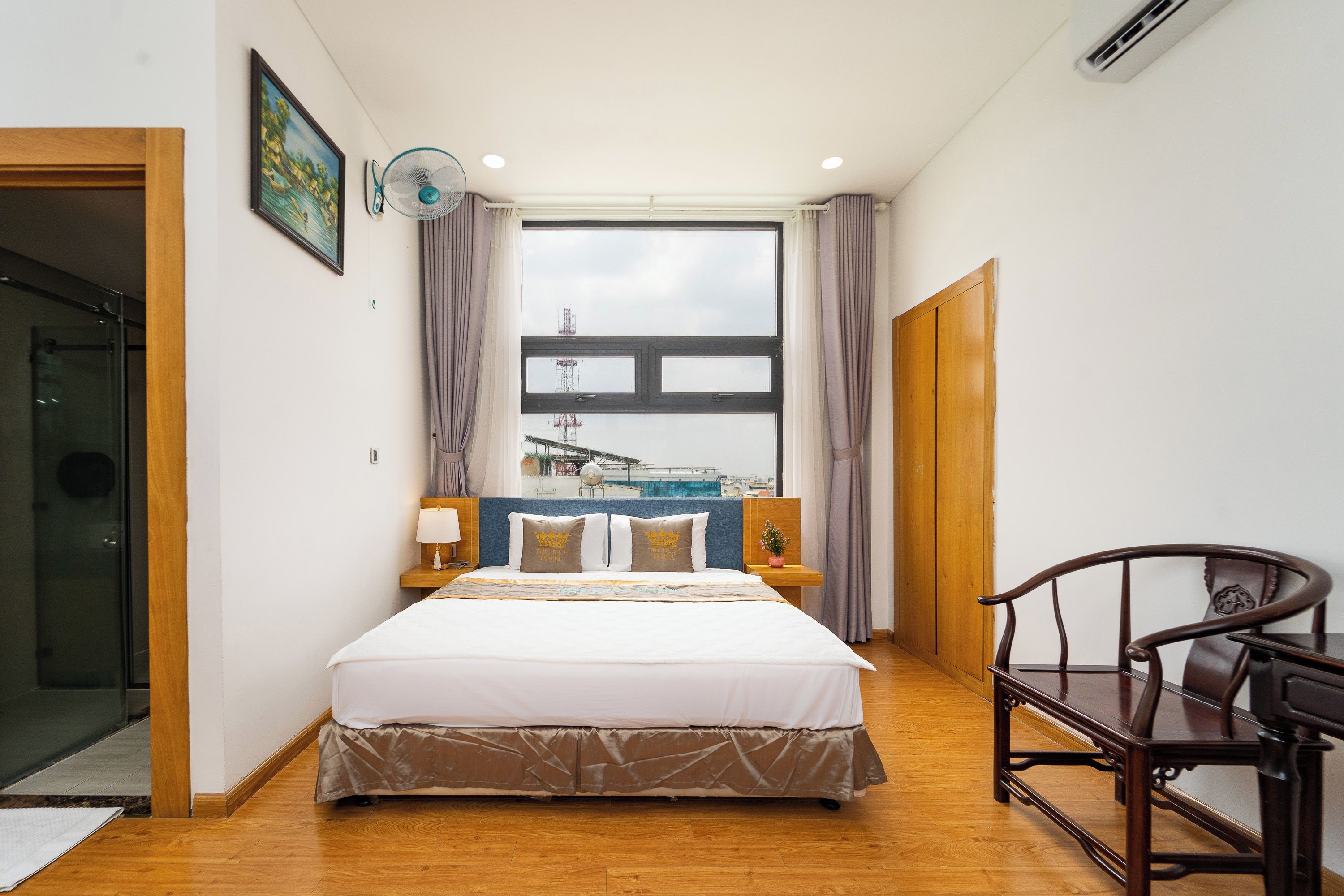 Une chambre d’hôtel avec un lit, une table de chevet, une lampe, une chaise et une vue sur un pont et sur l’eau.