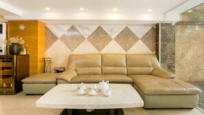 Uma sala de estar moderna com um sofá seccional, uma mesa de centro com bules e uma parede decorativa com padrão geométrico.