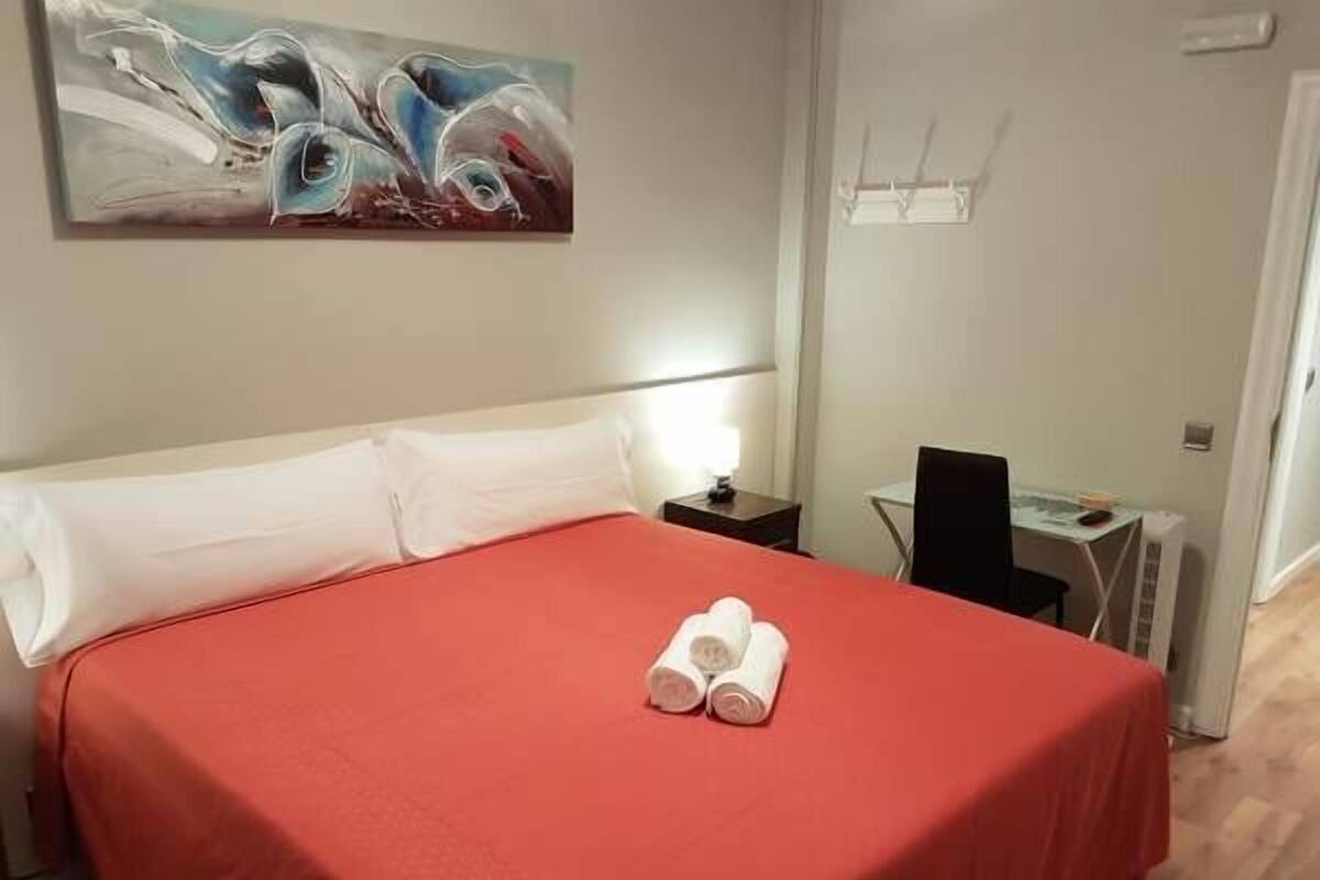 Una habitación de hotel con una cama, un escritorio y un cuadro en la pared.