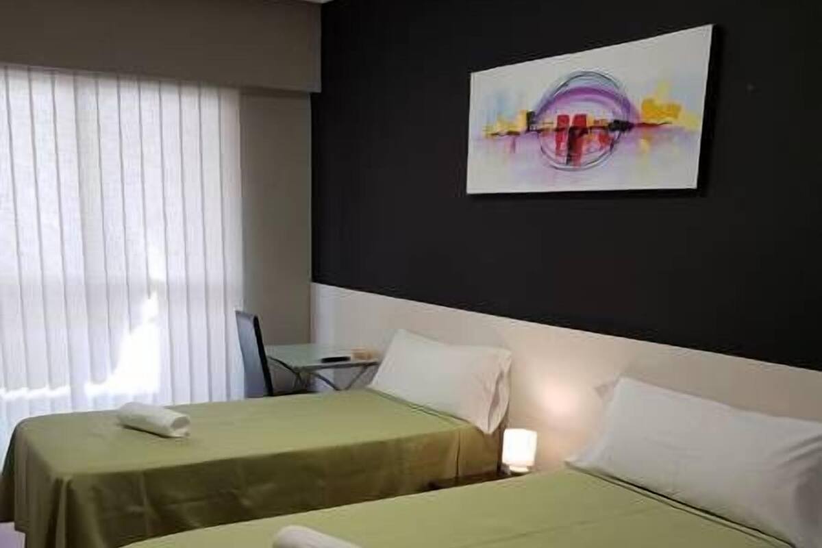 Una habitación de hotel con dos camas, un escritorio pequeño y un cuadro en la pared.