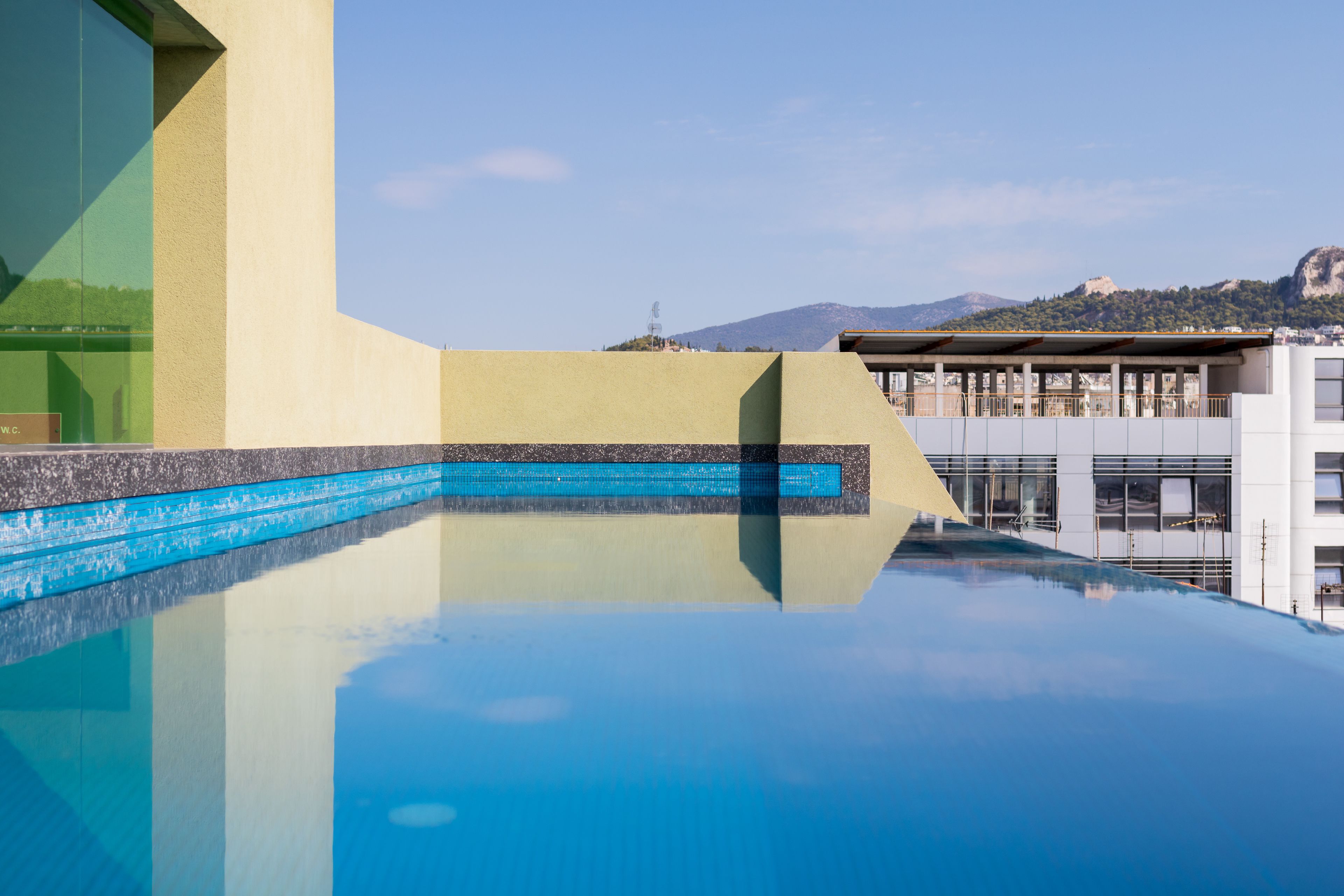A rooftop swimming pool with a clear view of a mountain in the background.