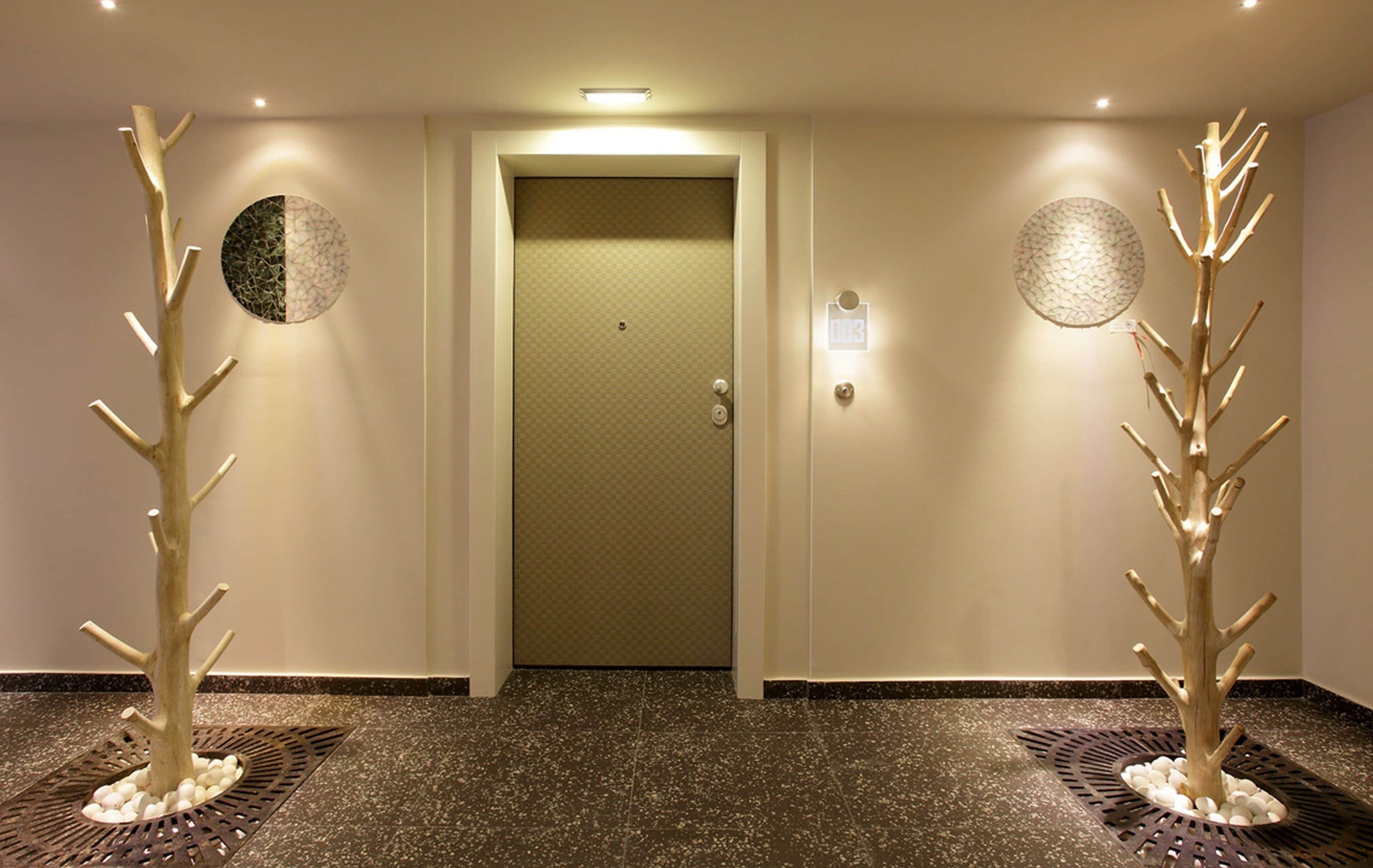 A hallway with a door, two tree-like sculptures, and patterned wall decor.