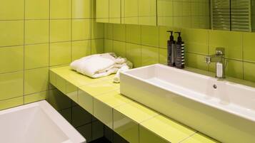 A bathroom with a white sink, green tiles, and a white bathtub.