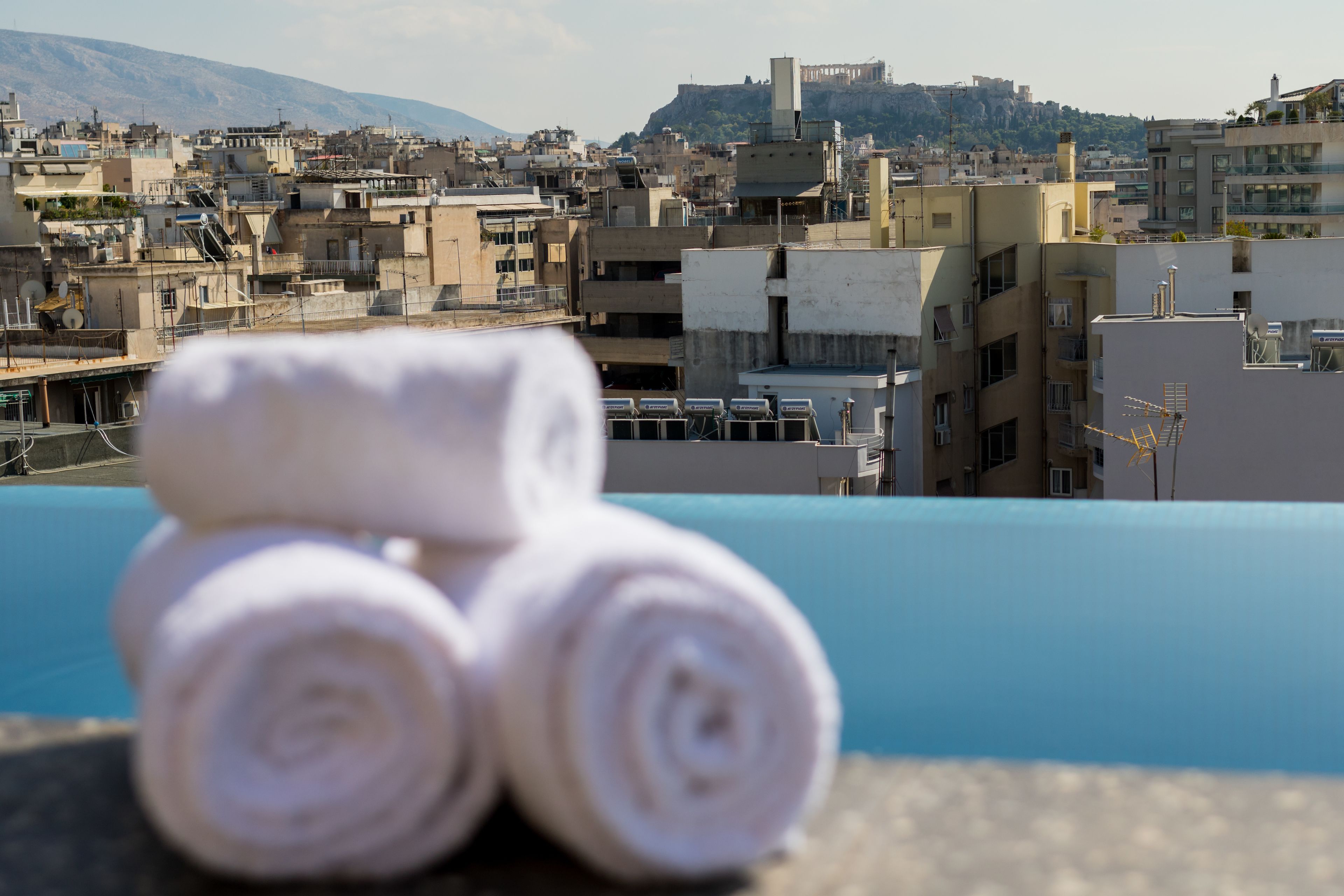 Una terraza con toallas dobladas y vistas a una zona urbana densamente poblada, con edificios y una colina al fondo.