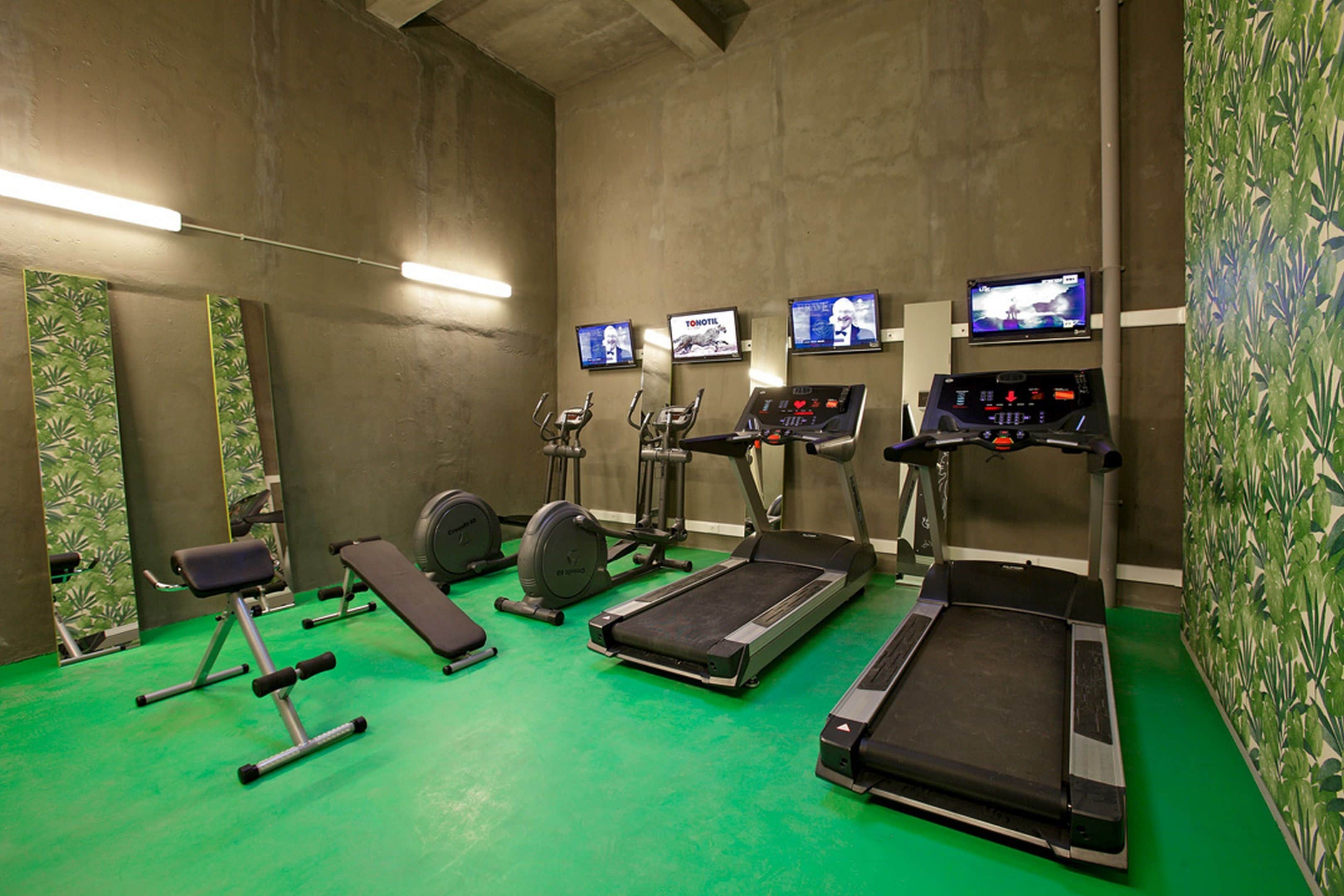 Une salle de sport équipée de tapis de course, de vélos d’appartement et d’appareils de musculation.