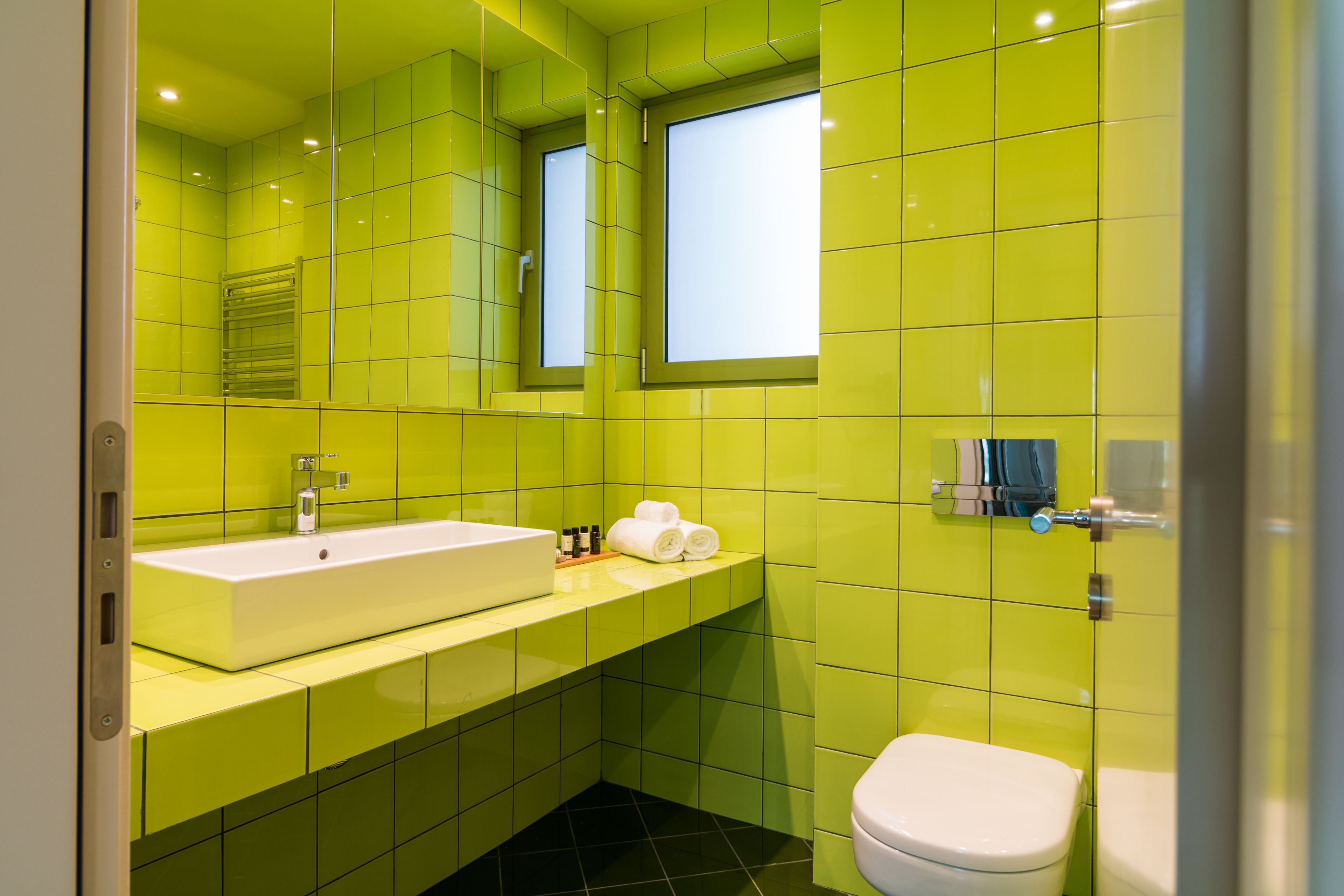 Ein Badezimmer mit einem großen, weißen Waschbecken, einer Toilette und einem Spiegel.