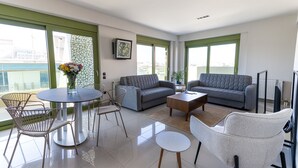 A modern living room with a sofa, two armchairs, a coffee table, and a dining table with chairs. - Athens Mosaico Suites and Apartments (Athens)