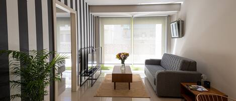 A modern living room with a sofa, coffee table, and a potted plant.