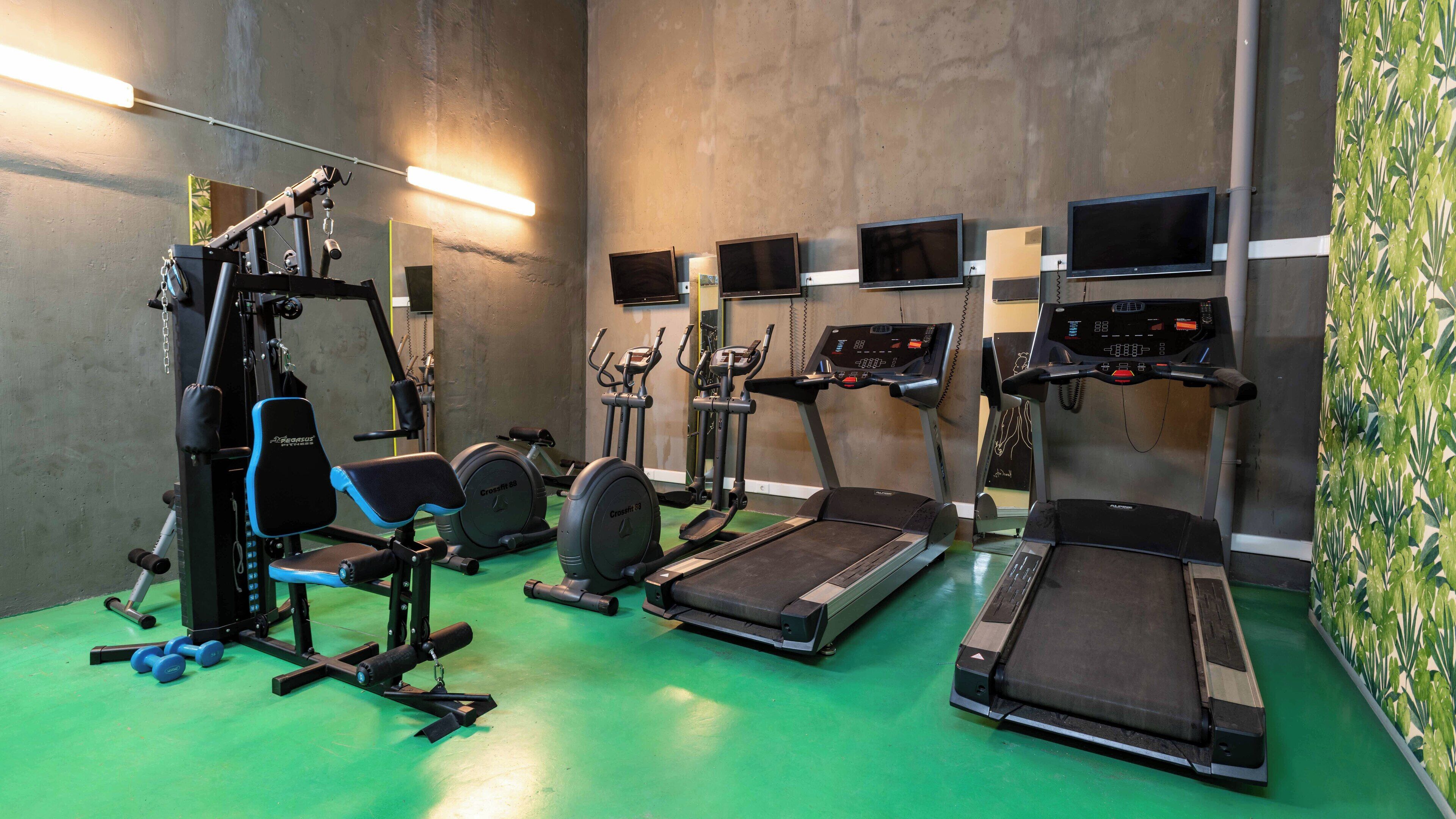 A gym with treadmills, elliptical machines, weight machines, and free weights.