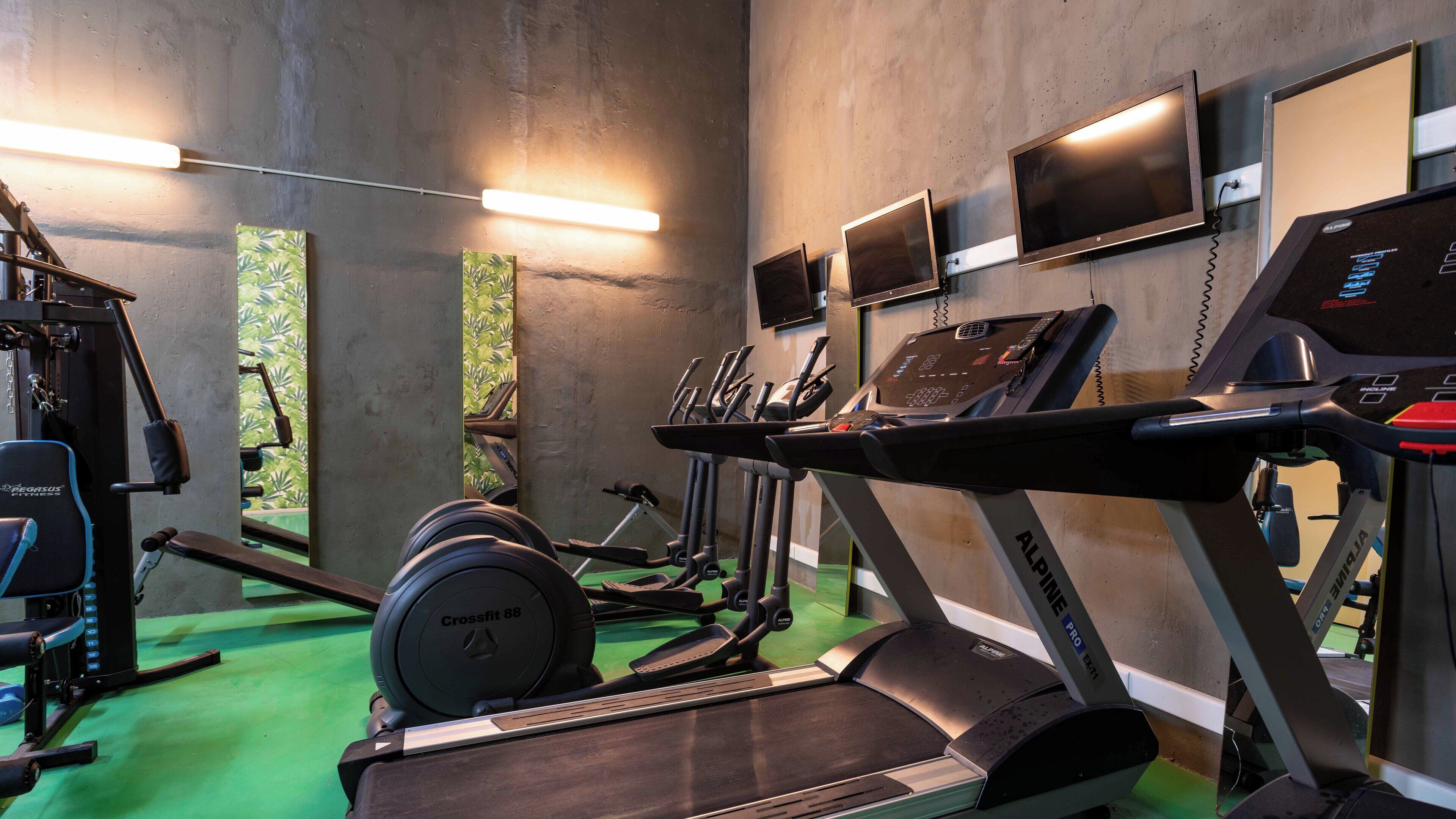 A gym with treadmills, a crossfit station, and weightlifting equipment.