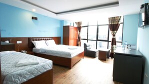 Habitación de hotel con dos camas, un escritorio, un armario y vistas a la ciudad.