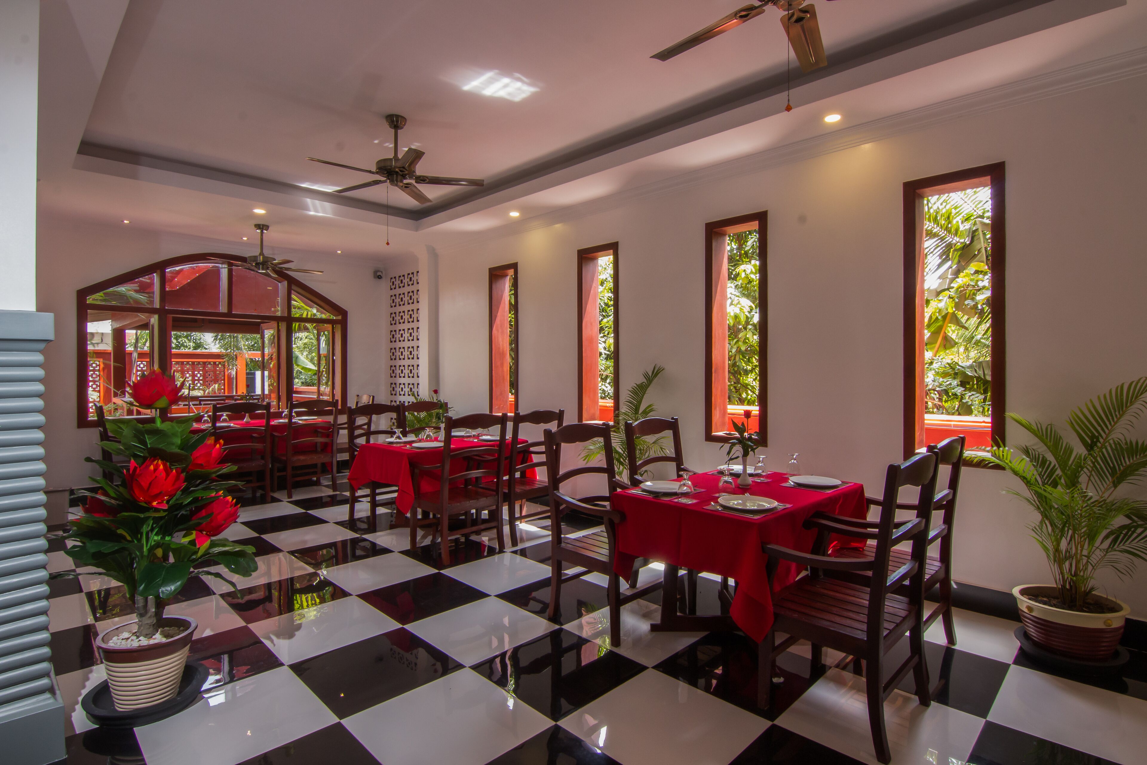 A restaurant with checkered flooring, red tablecloths, and wooden chairs.