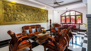 A dining area with wooden furniture, a large decorative wall, and a view of the outdoors. - Bou Savy Villa (Siem Reap)