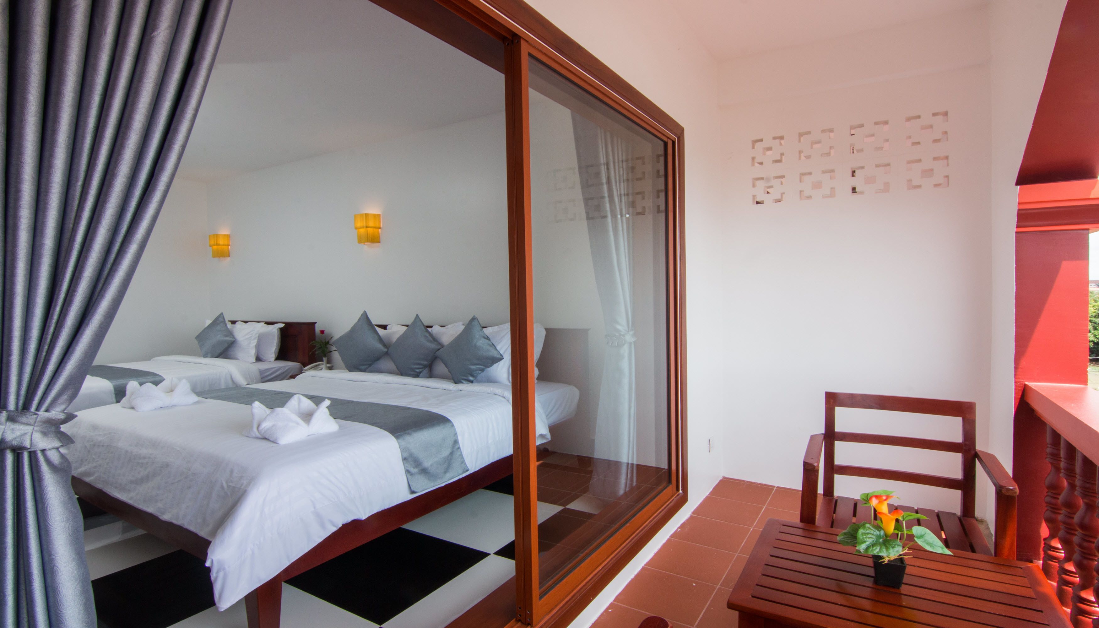 A hotel room with a large bed, two bedside tables, a chair, and a small table with a plant.
