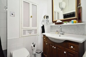 A bathroom with a toilet, sink, mirror, and cabinet.